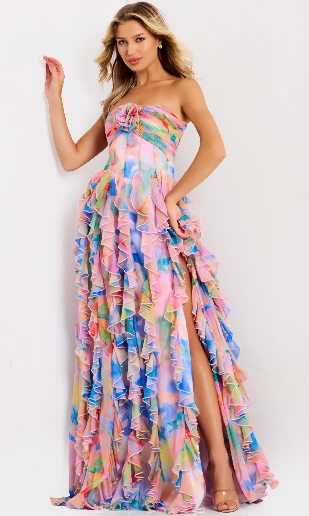 A woman models the Jovani 46381 long prom dress—a strapless chiffon gown featuring multicolored ruffles and a high slit—against a plain white background.